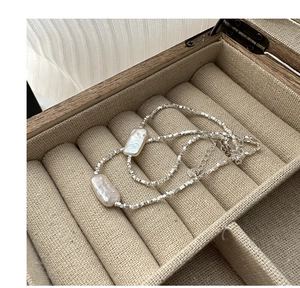 Close-up of irregular baroque pearls and silver square beads on an elegant necklace