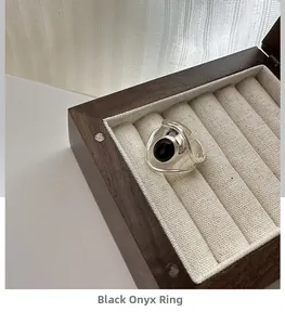 Close-up of vintage oval black agate silver ring displayed in a dark wooden jewelry box