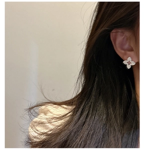 Gros plan de boucles d'oreilles trèfle en argent S925 avec centre rouge sur l'oreille