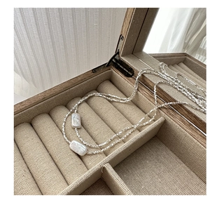 Detail of a minimalist S925 silver necklace with rectangular pearls in a jewelry box