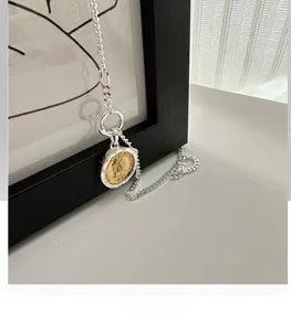 Detail of S925 silver necklace with two-tone gold coin pendant on a wooden frame