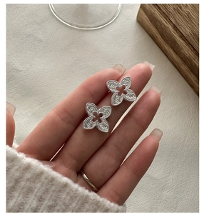 Gros plan de boucles d'oreilles trèfle en argent S925 avec texture tourbillon rétro