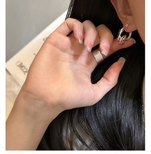 Macro view of minimalist S925 sterling silver knot earrings and polished wide band ring