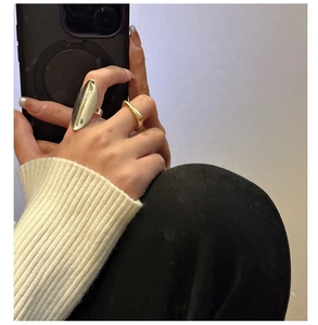 Detail of silver oval dome ring and gold square thin band worn on a hand for a trendy look
