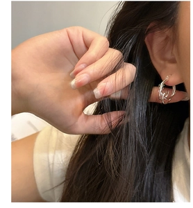 Detail of minimalist S925 silver knot hoop earrings worn by model for a trendy look