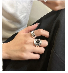 Close-up of a wide silver ring paired with an oval black onyx gemstone ring on a hand