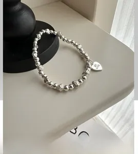 Detailed macro of S925 silver beaded bracelet with heart pendant and Be Mine engraving