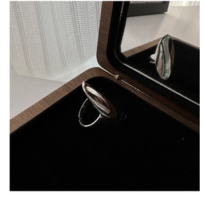 Macro detail of minimalist S925 sterling silver ring with polished organic wave surface