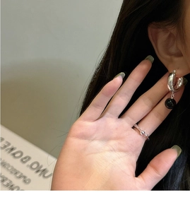 Gros plan d'une boucle d'oreille en argent 925 avec agate noire et bague ondulée