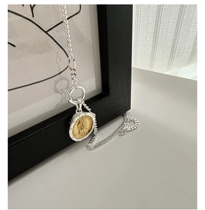 Macro shot of S925 silver necklace with two-tone Elizabeth II coin pendant detail