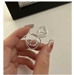 Detailed close-up of S925 sterling silver knotted hoop earrings with hallmark stamp
