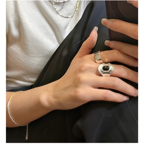 Macro detail of oval black agate silver wide ring and minimalist jewelry styled on hand