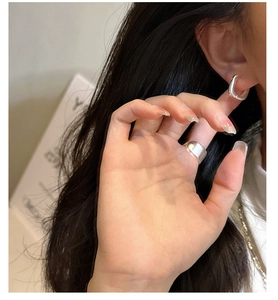 Gros plan de boucles d'oreilles carrées en argent S925 et d'une bague large sur modèle