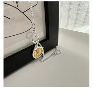 Detailed macro of vintage silver S925 necklace with gold coin pendant featuring Queen Elizabeth