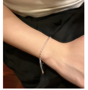 Detail view of a minimalist S925 sterling silver beaded chain bracelet on a wrist