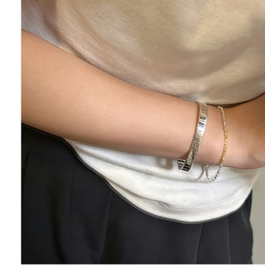 Detail of S925 sterling silver gear bracelet styled with mixed metal chain on wrist