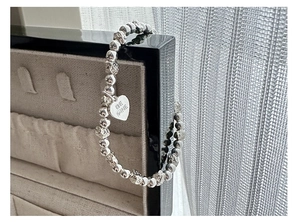 Close-up of S925 silver beaded bracelet with heart pendant engraved Be Mine