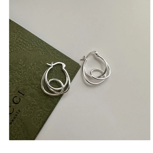 Macro shot of S925 sterling silver knotted hoop earrings with polished metal texture