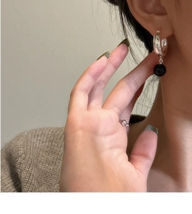 Détail de boucles d'oreilles créoles en argent 925 avec pendentif onyx noir porté
