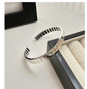 Macro shot of S925 sterling silver cuff bracelet showing vertical stripe texture and hallmark