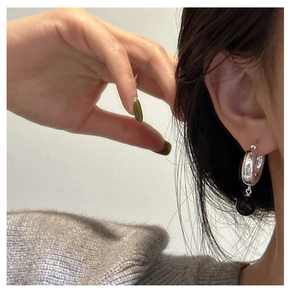 Gros plan de créoles en argent sterling 925 avec pendentif perle d'onyx sur un modèle