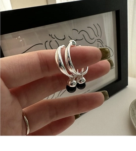 Close-up of S925 silver hoop earrings with black onyx bead charms and a thin ring