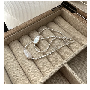 Close-up of baroque pearls on silver faceted bead chain inside a wooden jewelry box