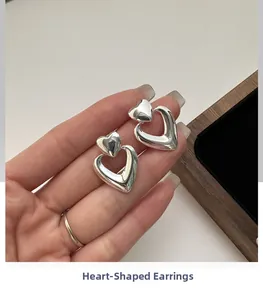 Macro view of double layered silver heart earrings held to show texture and size