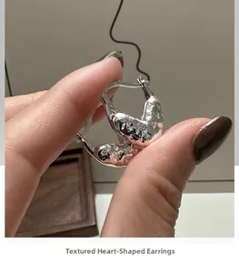 Gros plan sur des créoles en forme de cœur en argent S925 avec texture effet lave