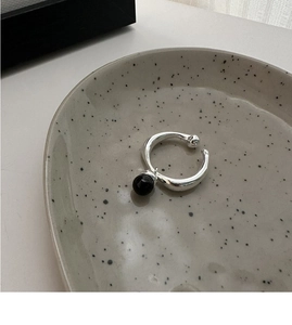 Detail of 925 silver ring with black onyx bead pendant on a ceramic plate