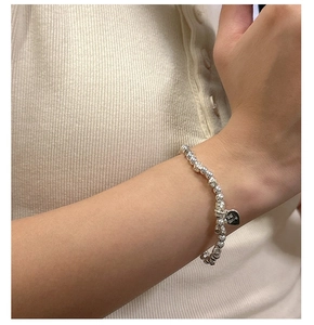 Macro view of silver bead bracelet featuring a heart charm engraved with BE MINE text