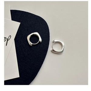 Détail macro de boucles d'oreilles créoles carrées en argent avec finition brossée