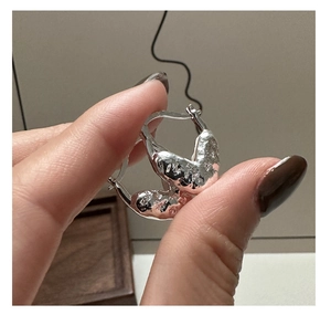 Détail de boucles d'oreilles en argent S925 avec texture de lave irrégulière à la main