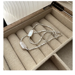 Close-up of square silver beads and baroque pearls on a 925 silver bracelet in a jewelry box