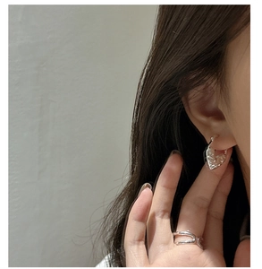 Détail des boucles d'oreilles cœur en argent S925 avec une texture martelée élégante