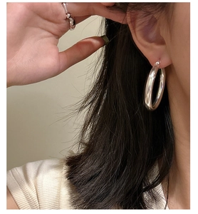 Polished S925 sterling silver large hoop earrings worn by a model in a close-up shot
