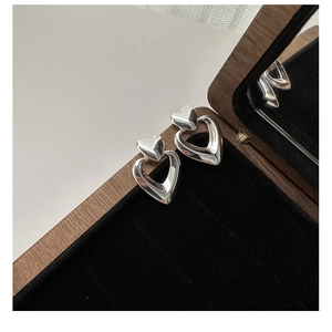 Macro detail of S925 sterling silver double heart earrings on a premium black velvet box