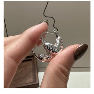 Gros plan de créoles en argent sterling S925 avec texture liquide de lave irrégulière