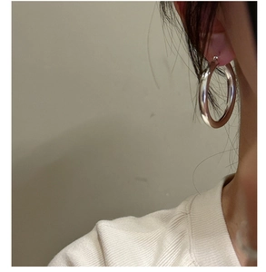 Macro shot of large polished S925 sterling silver hoop earrings worn by a model