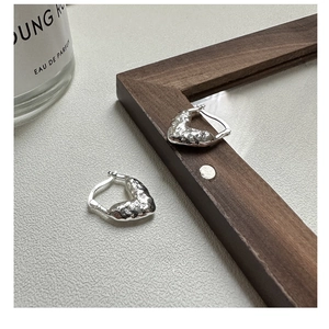 Gros plan de boucles d'oreilles cœur en argent avec texture martelée et poinçon S925