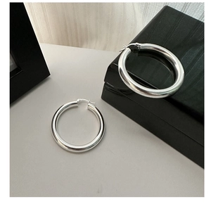 Detailed view of polished S925 sterling silver hoop earrings on a decorative jewelry box