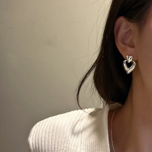 S925 sterling silver layered heart drop earrings shown on model in warm studio lighting