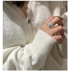 Close-up of S925 sterling silver ring with irregular liquid metal texture on knitwear