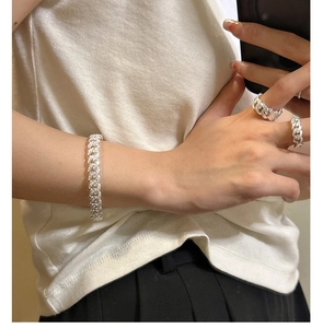 Detail of silver Cuban link bracelet and rings set with pavé cubic zirconia