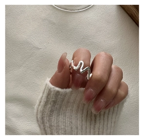 Gros plan d'une bague vague minimaliste en argent sterling S925 portée sur la main douce