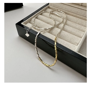 Detail view of S925 sterling silver beaded necklace with golden heart charm on velvet tray