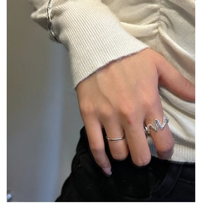 Gros plan sur la bague ondulée en argent S925 et le bracelet minimaliste sur un pull