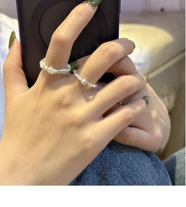 Détail d'une bague en argent S925 et d'une bague en perles baroques portée à la main
