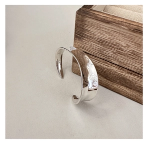 Detailed close-up of a silver polished open cuff bracelet with wavy texture and mirror finish