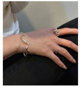 Détail macro de bracelets et bagues vagues argentés au design fluide irrégulier